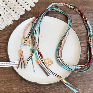 Detail of bohemian layered necklace with tiger eye beads and heart charms on white tray