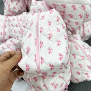 Close-up of quilted cosmetic bag with pink bow pattern and functional zipper detail