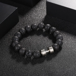 Gros plan de perles en pierre de lave noire et breloque haltère sur un bracelet masculin