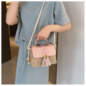 Detail of pink leather flap saddle bag with straw weave texture and stylish tassels
