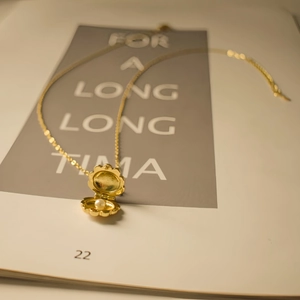 Detail view of a vintage gold shell locket necklace with a white pearl inside