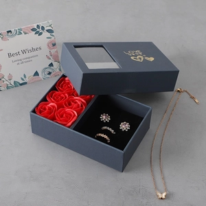 Detailed top view of blue gift box with six red soap roses and elegant jewelry set
