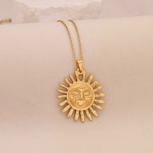 Detail of creative gold sun face pendant on stainless steel necklace over stone base