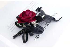 Détail de la boutonnière rose en velours rouge foncé et calla noir avec ruban noir et or