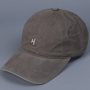 Macro shot of white H embroidery detail on washed dark grey cotton baseball cap