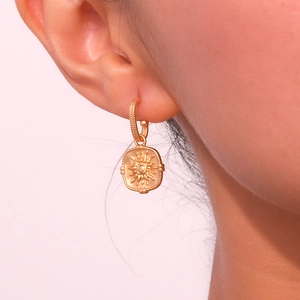 Detailed close-up of vintage golden sun embossed earrings worn by a model