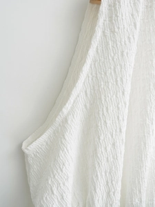 Nahaufnahme des weißen rückenfreien Oberteils mit Plissee-Textur und minimalistischem Design