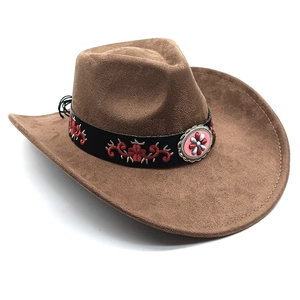 Detail of western cowboy hat with brown suede texture, black embroidery band and metal badge