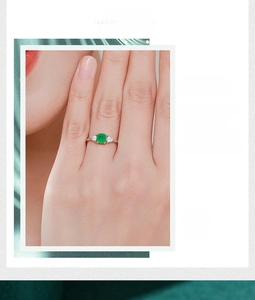 Detail of s925 silver ring featuring round green emerald stone and side triangle zircons