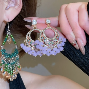 Close-up of bohemian earrings with crystal tassels and colorful rhinestone details