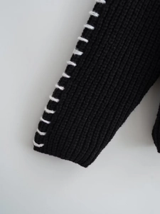 Dettaglio della manica in maglia nera con cuciture bianche a contrasto decorative