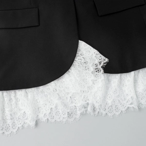 Close-up of elegant white eyelash lace trim on the hem of a black blazer jacket