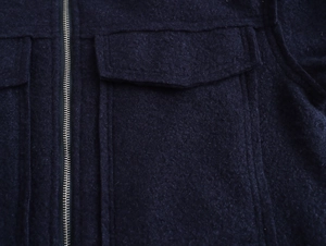 Détail macro du tissu texturé dense et de la fermeture éclair métallique de la veste