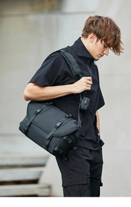 Detail of black tactical messenger bag featuring flap buckles and adjustable strap pouch