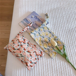 Detail of floral mini cotton hand bags on a cozy white bed with a warm tulip background