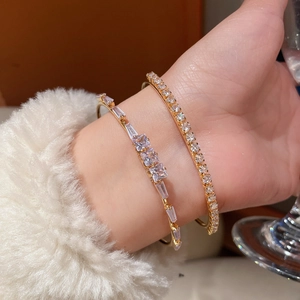 Close-up of 18K gold plated stackable bracelets with square zircon stones on a soft sleeve
