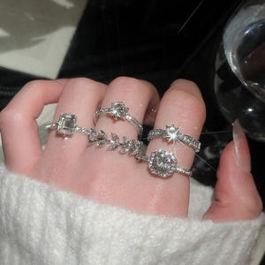 Macro detail of silver geometric zircon rings set worn with white knit sweater