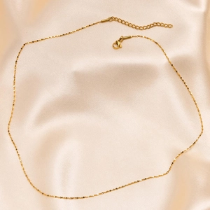 Detail of 18k gold plated titanium steel chain with lobster clasp on silk fabric