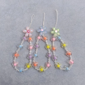 Detailed shot of handmade floral beaded phone charms in pink blue and green acrylic