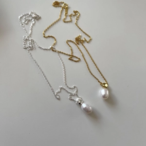 Detail of silver and gold teardrop pearl necklaces with delicate metal chains on white background