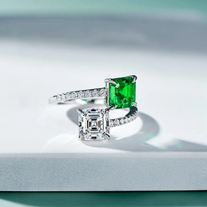 Macro view of dual-stone ring with emerald and princess-cut diamond on a silver band