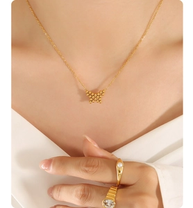 Close-up of golden butterfly pendant necklace with beaded texture on a model