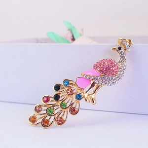 Golden peacock keychain with colorful rhinestones on a white gift box with floral accents