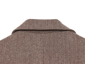 Detailed close-up of brown herringbone wool fabric texture on a blazer collar