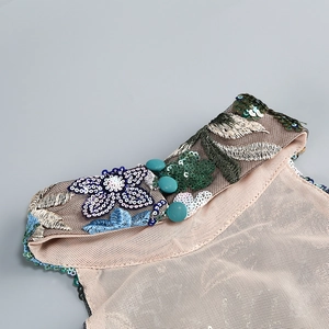 Detailed embroidery and sequins on a peach slim-fit halter neck dress with decorative buttons