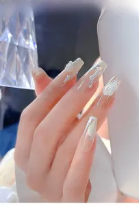 Detail of long coffin press-on nails with white 3D gypsum flower relief and crystals