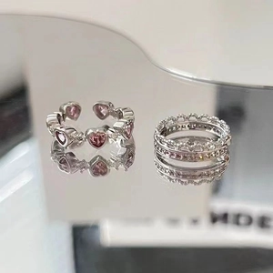 Detail of silver heart rings with pink zircons and crown pavé setting on mirror surface