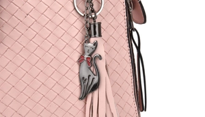 Close-up of pink woven handbag with a cute cat metal charm and matching tassel detail