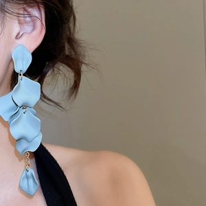 Close-up of matte blue acrylic petal tassel earrings worn by a model in a side view