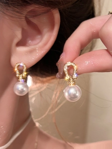 Close-up of 18K gold plated horseshoe earrings with zircon and white pearls on model