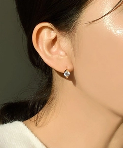 Close-up of golden zircon stud earring on ear with high polish and sparkling stone