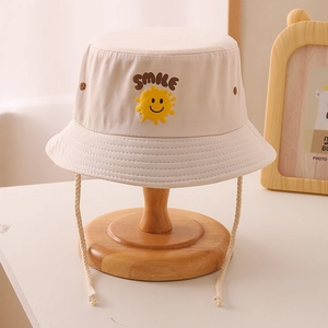 Détail d'un chapeau bob beige pour enfant avec broderie Smile et cordon coupe-vent tissé