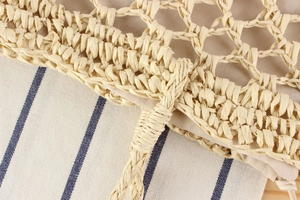 Detail of hand-woven straw bag with beige texture and blue striped fabric lining