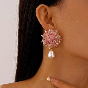 Pink fabric floral earrings with teardrop pearls and crystals worn by a model