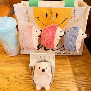 Plush hedgehog keychain set in pink, red, blue, and gray on a canvas backpack