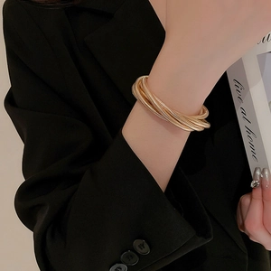Close-up of a wide triple-layer metallic gold coiled snake bone bracelet on a model