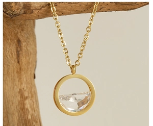 Close-up of a hollow circular 18K gold necklace pendant with clear zircon on a branch