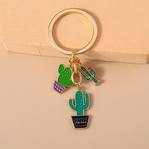 Close-up of golden keychain with three green enamel cactus charms featuring hello text