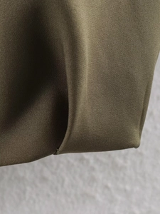 Macro shot showing olive green pleated hem and woven fabric texture of bomber jacket