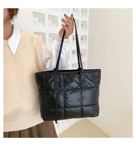 Detail of black quilted puffer tote bag with glossy finish and soft padded nylon texture