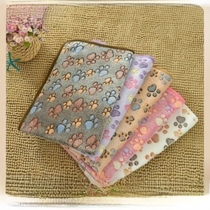 Close-up of soft flannel pet blankets with paw prints in multiple colors and stitched edges