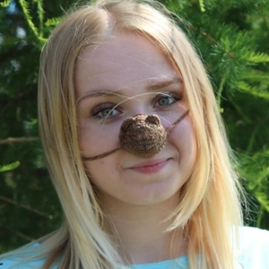 Detail of handmade crochet brown bear nose warmer worn by model in outdoor setting