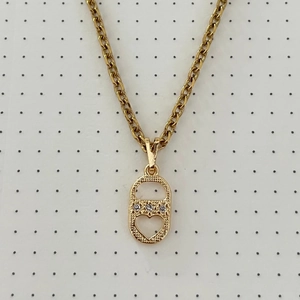 Macro detail of gold chain necklace featuring a CD-style heart pendant with inlaid crystals