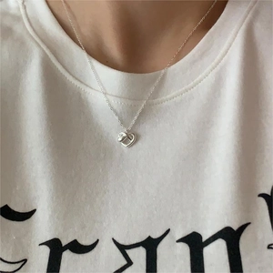 Detail of 925 sterling silver heart-shaped knot pendant necklace worn on model