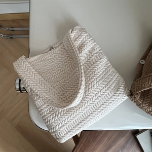 Detailed view of beige woven handbag texture with thick fishbone knit pattern