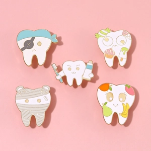 Detailed flat lay of five unique cartoon tooth enamel pins on a soft pink background